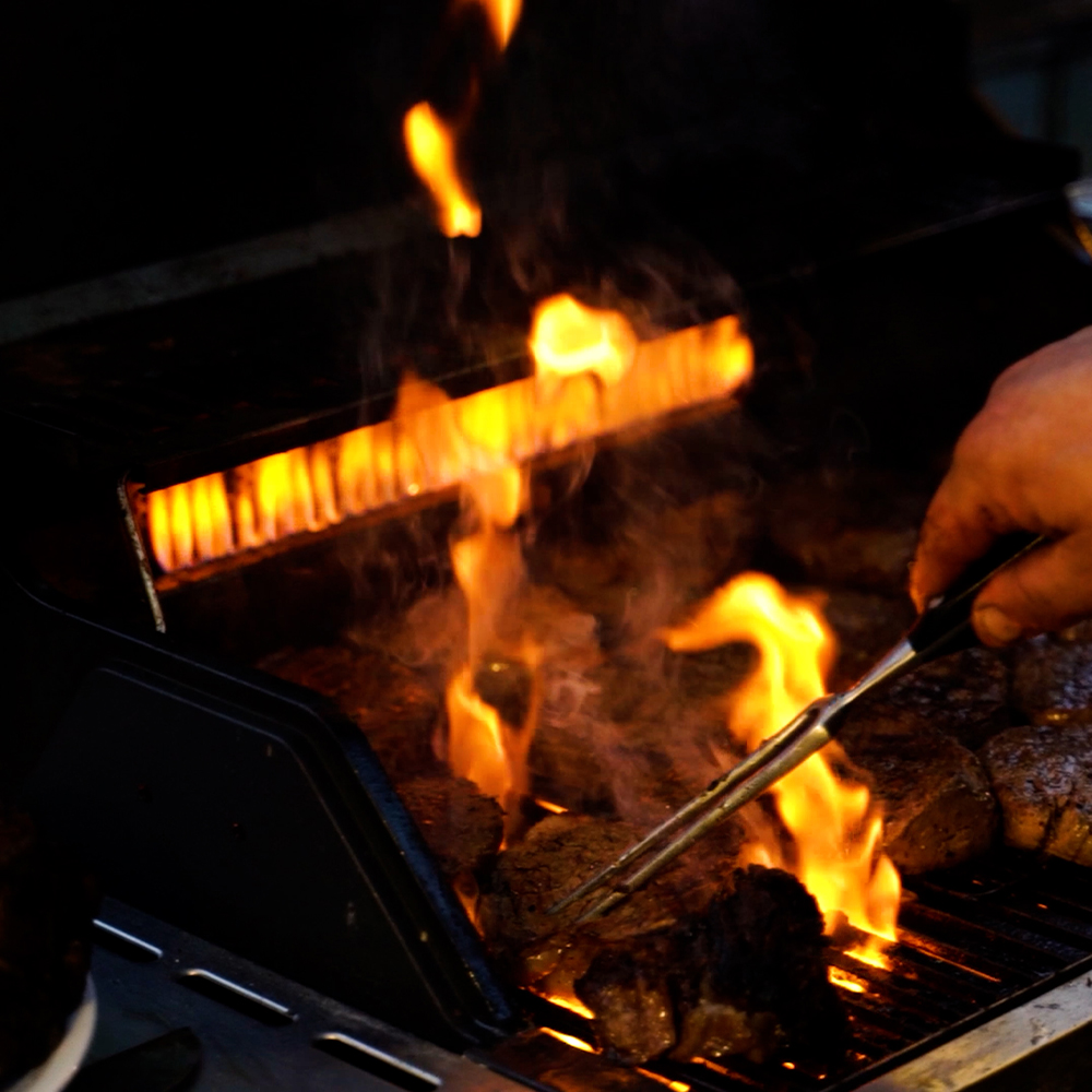 Fleisch wird gegrillt und gewendet - Hochzeitscatering