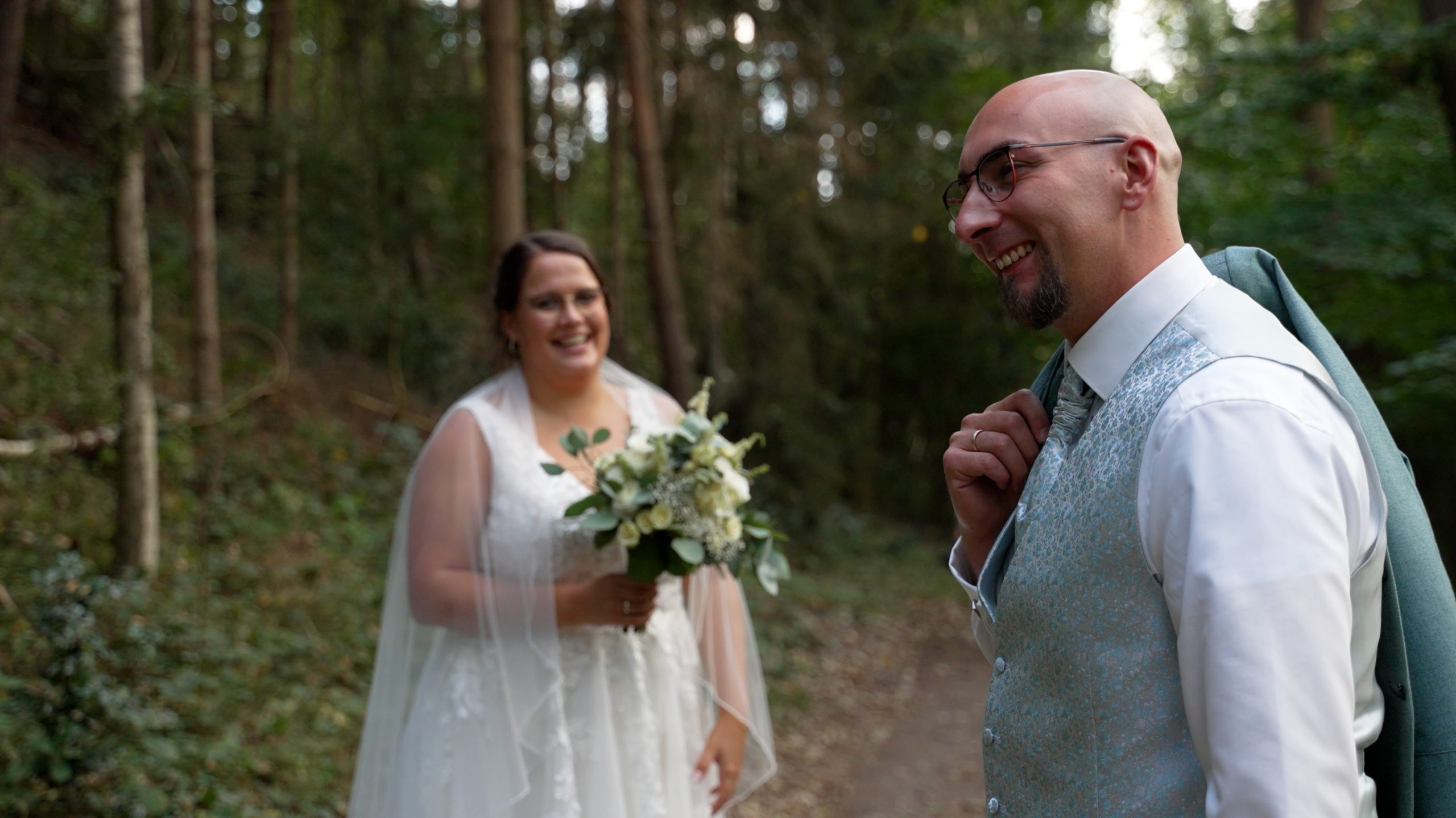Brautpaar im Wald locker mit Brautstrauß lächelnd